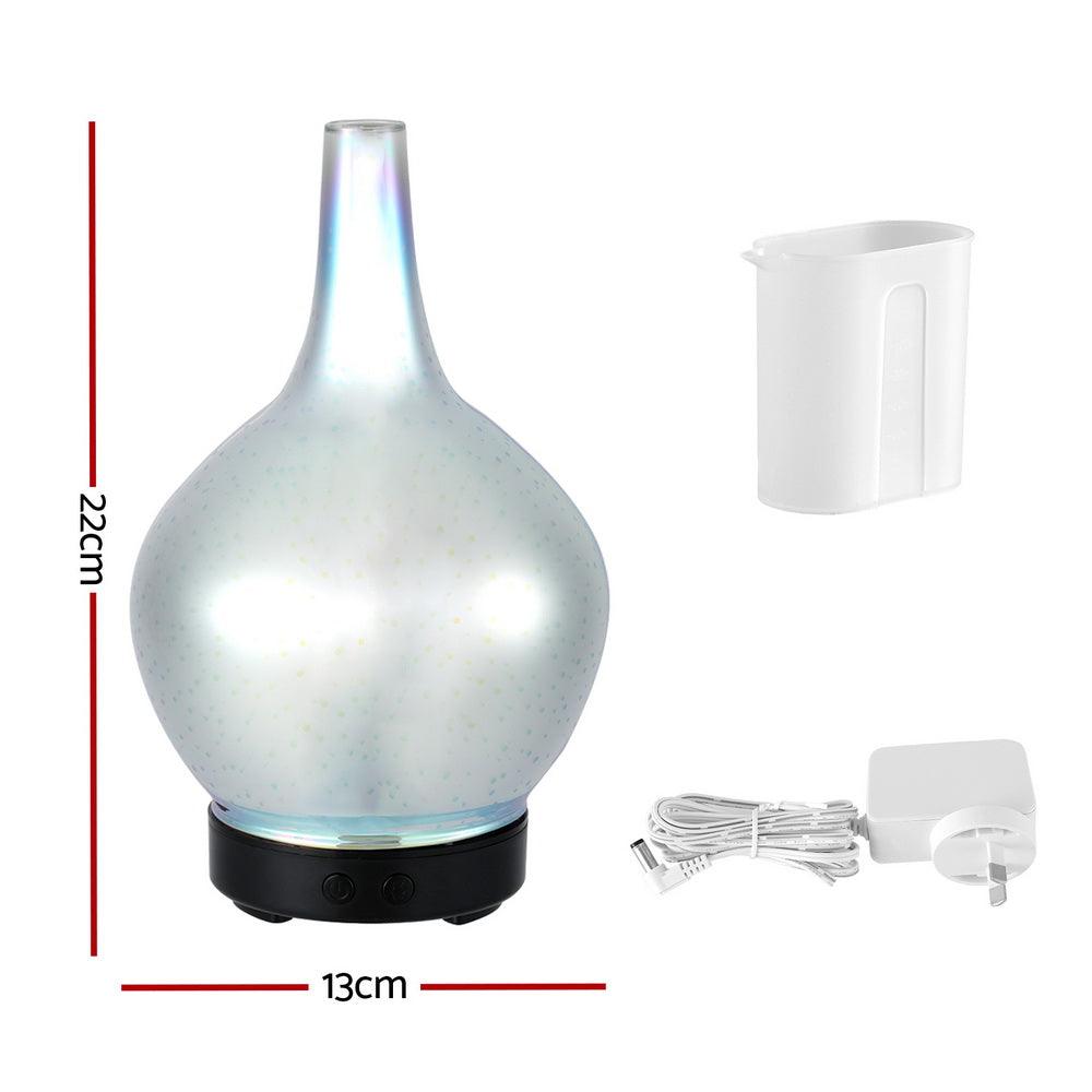 Glass aroma diffuser with iridescent finish, measuring 22cm high by 13cm wide, shown with water measuring cup and power adapter.