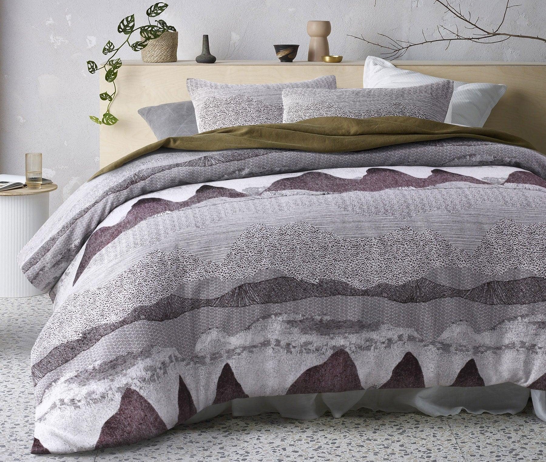 Contemporary bedroom with a patterned burgundy and grey quilt cover set on a neatly made bed